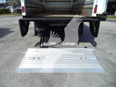 Isuzu NPR-HD box truck rear with lowered aluminum ramp in open cargo bed and taillights visible.