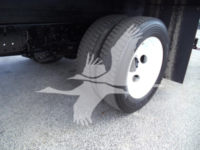 Isuzu NPR HD truck wheel and front tire visible underbox with white steel rim and dual rear axle, some chassis components visible.