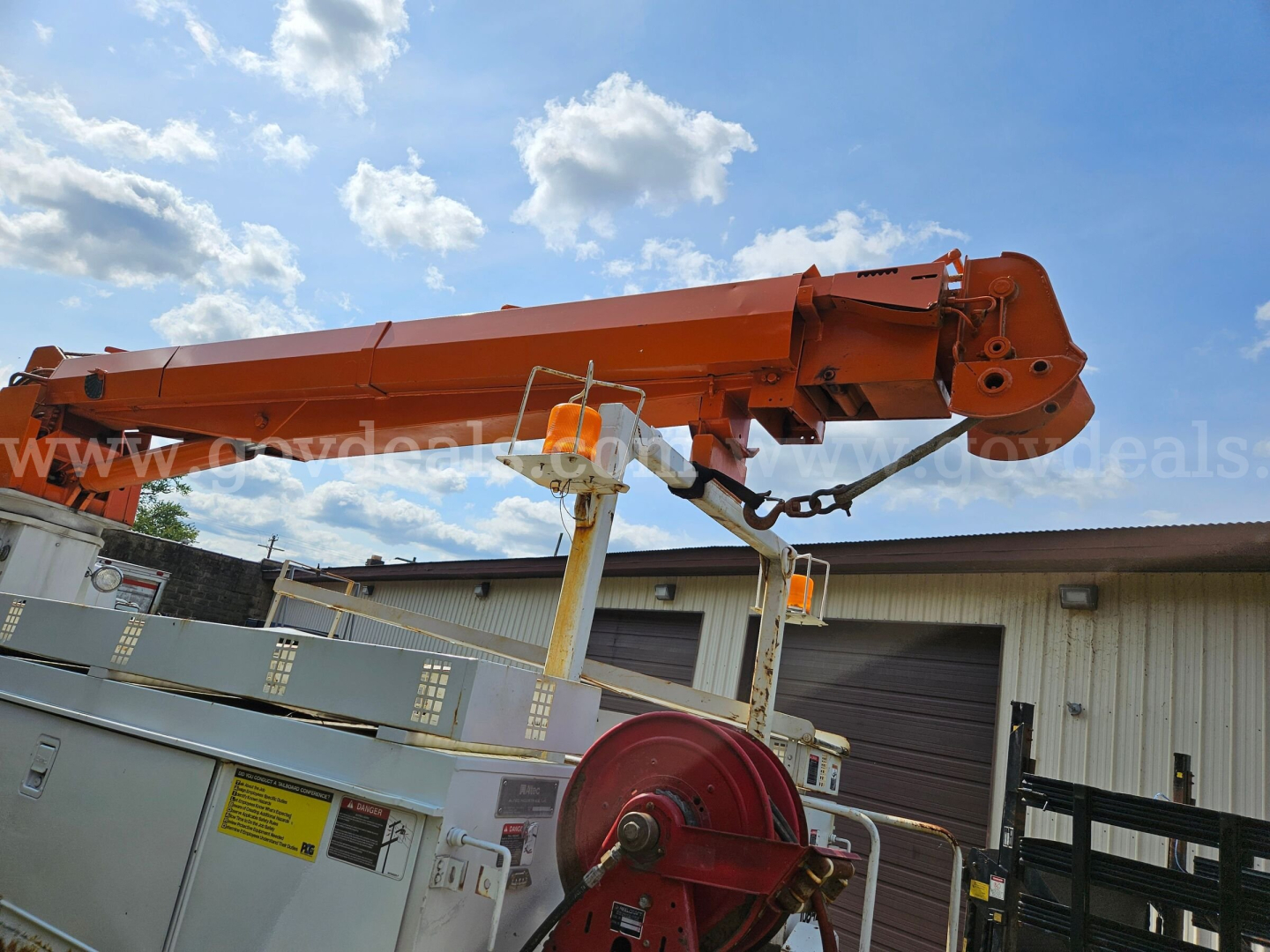 Exterior of a 1995 International 4900 boom truck with an extended orange crane arm resting above a silver utility bed.
