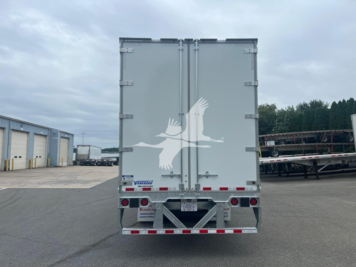 Back of a Vanguard Maxcube trailer showing large white bird logo on gray doors and reflective rear bumper with lights.