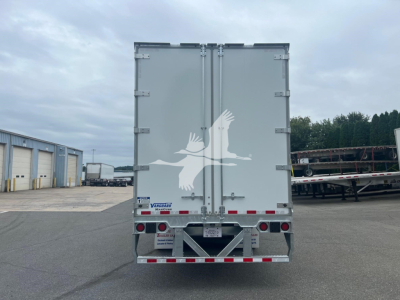 Back of a Vanguard Maxcube trailer showing large white bird logo on gray doors and reflective rear bumper with lights.