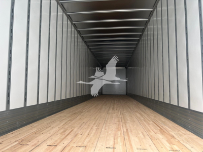 Trailer interior showing long empty cargo area with wooden floor and metal sidewalls, Vanguard branding watermark in center.