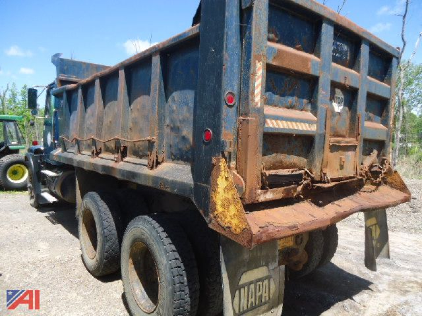 Dump truck bed view showing rear of a Volvo WG dump truck with rust and chain setup on tailgate