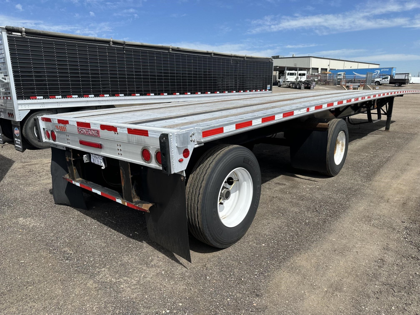 Fontaine spread air combination flatbed trailer showing aluminum deck, dual rear axles, and reflective safety tape.