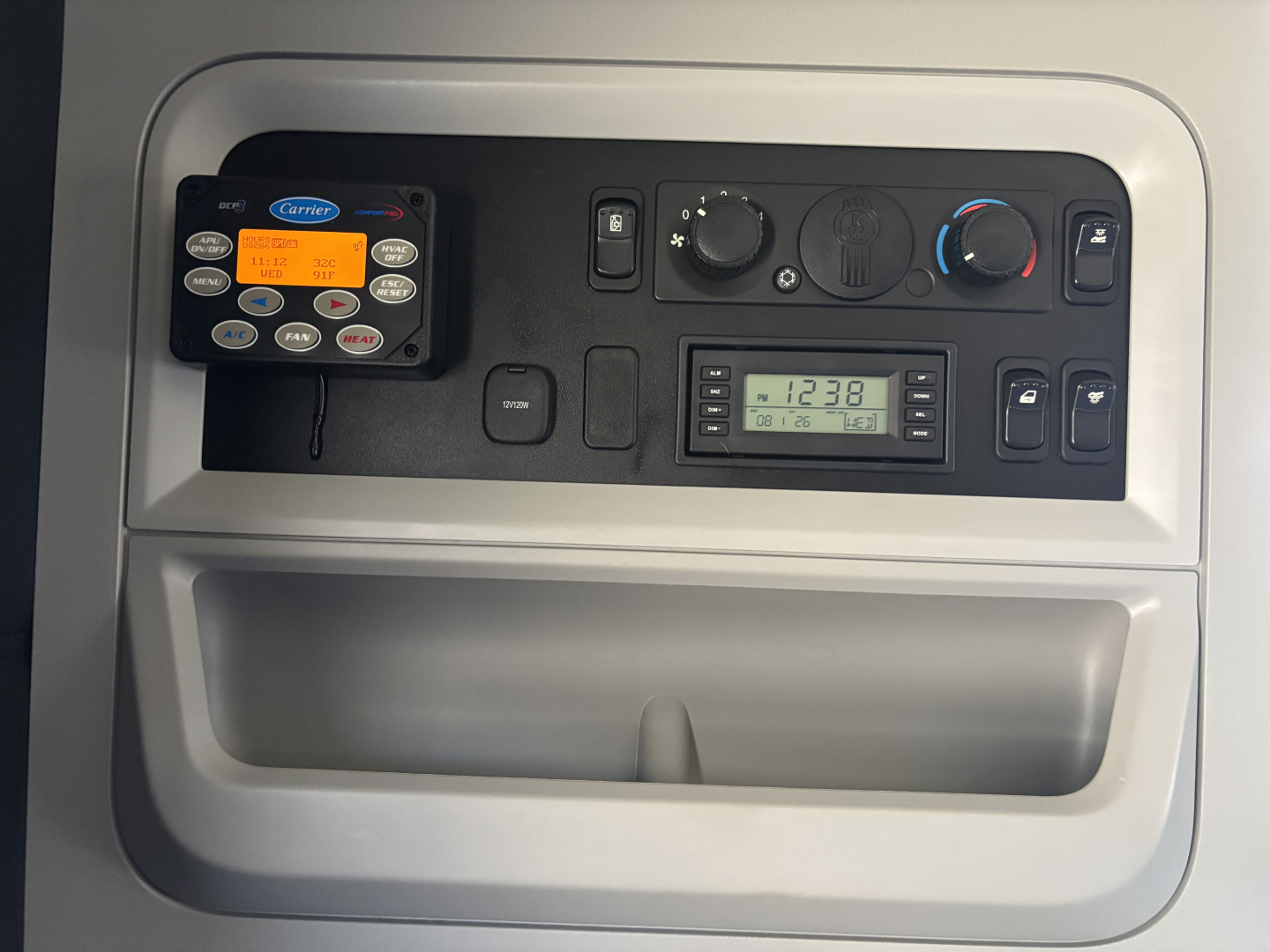 Kenworth T680 cockpit control panel showing nav/comm unit, HVAC controls, and digital gauge display in the dash console.
