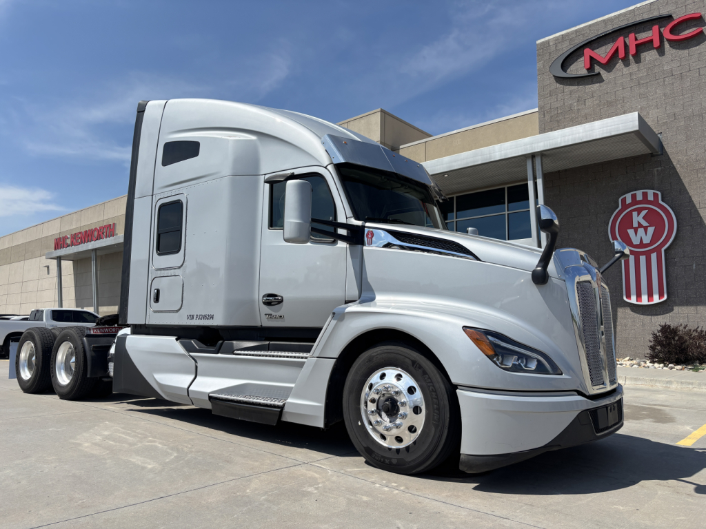 Kenworth T680 truck in a dealership lot, silver exterior, side view showing front grille and cab, daytime