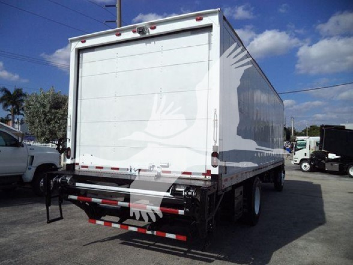 Isuzu box truck rear view showing large cargo area with reflective safety markings and rear underride guard.