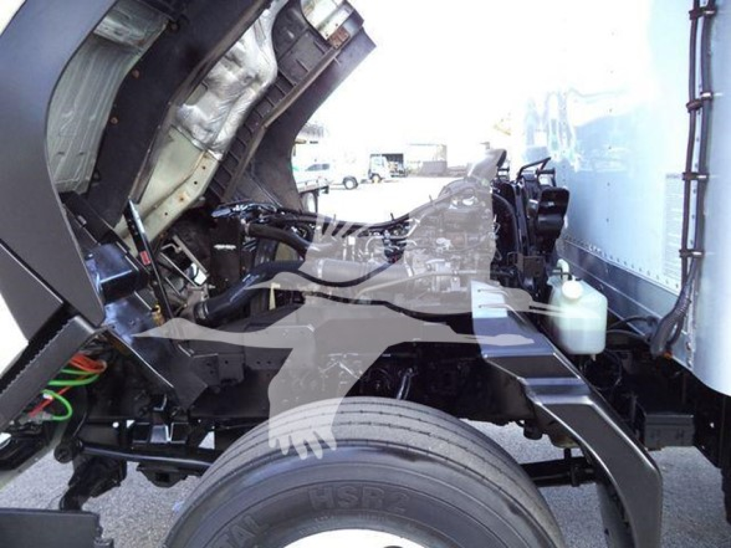Isuzu FTR cab forward truck engine bay showing frame rail, front wheel, and hydraulic lines.