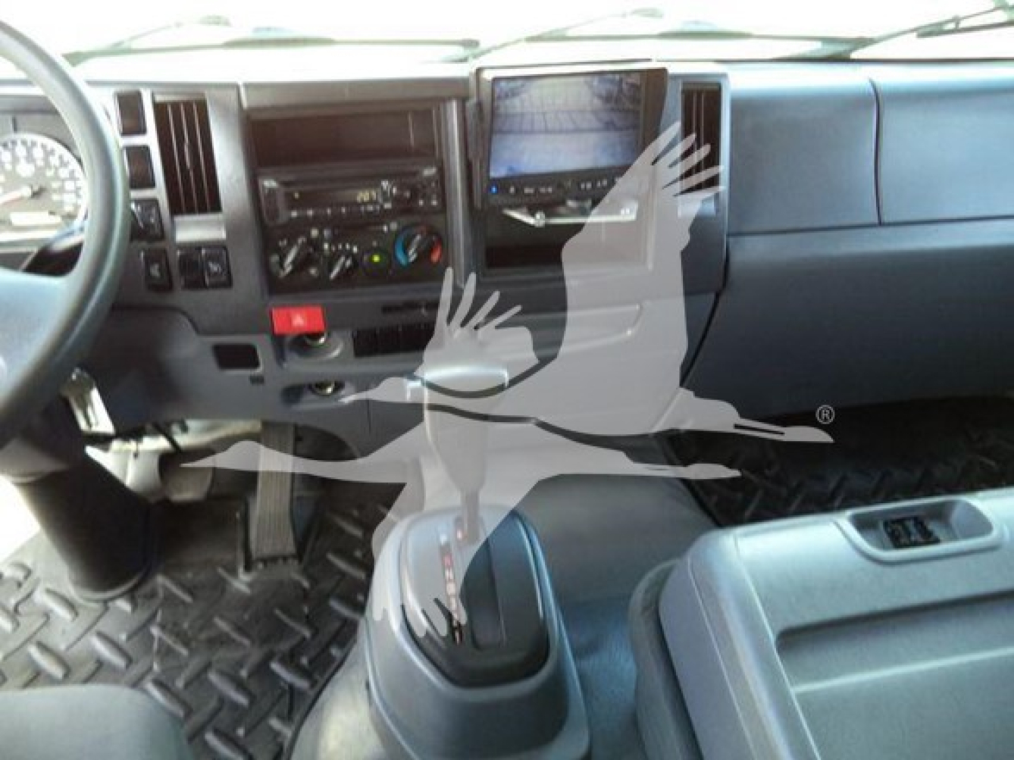 Isuzu FTR cab interior with manual shifter and dashboard controls; visible steering wheel, instrument cluster, and center console.