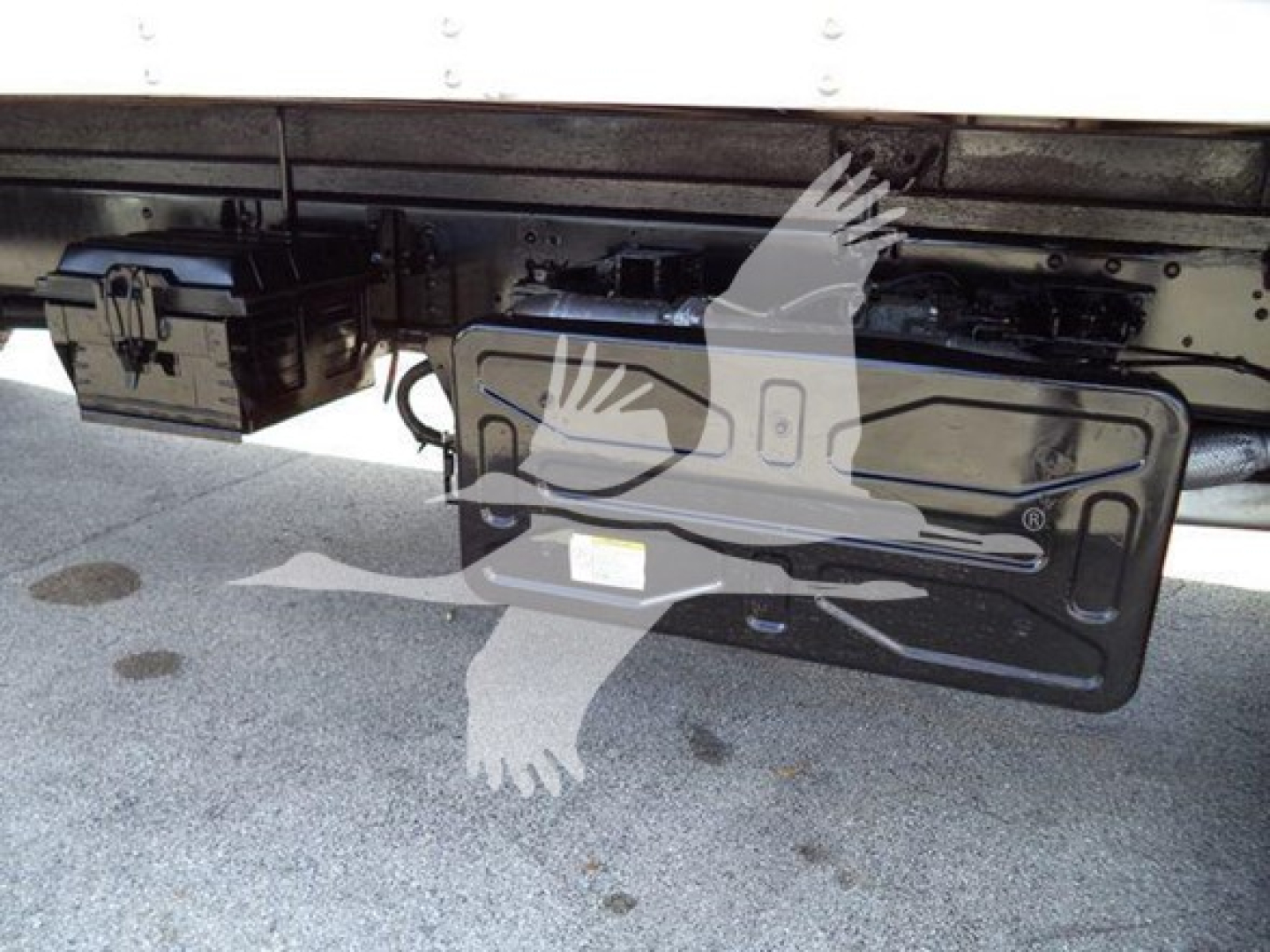 Isuzu truck undercarriage showing license plate area and wiring with a mounted battery box; no legible model text visible.