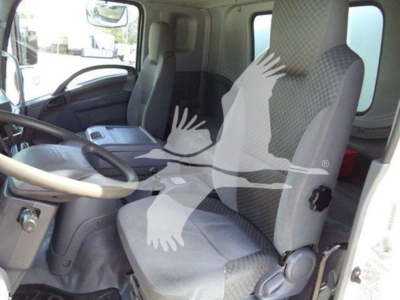 Isuzu FTR interior cabin view showing driver seat and passenger seat in front cab. Visible dashboard steering wheel and center console.
