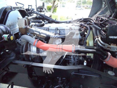 Isuzu FTR engine bay showing diesel engine with hoses and components visible in a box truck chassis.