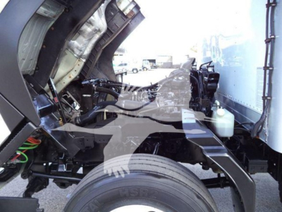 Isuzu FTR cab forward truck engine bay showing frame rail, front wheel, and hydraulic lines.