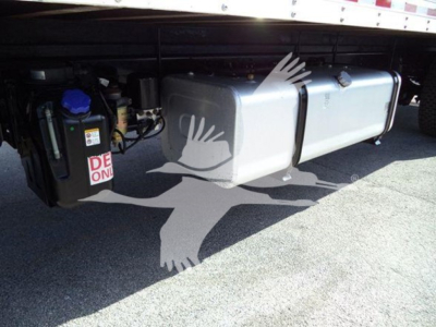 Isuzu FTR underbody showing large grey fuel tank and battery/engine components with blue cap reservoir; plastic/metal tank secured under truck.