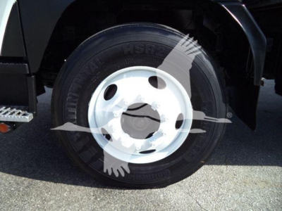 Isuzu truck wheel and tire in near-side front, with white wheel rim and black tire. Text on tire reads ‘Continental HSR’ and other tire markings faintly visible.