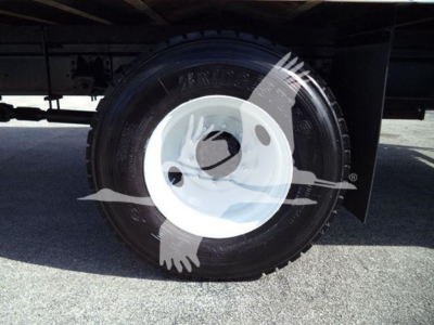 Isuzu FTR wheel/tire close-up showing steel white hub and black tire under truck bed.