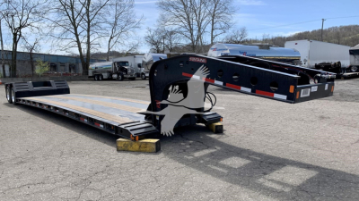 Fontaine lowboy trailer in service position showing long deck and gooseneck with black frame and reflective safety markings.