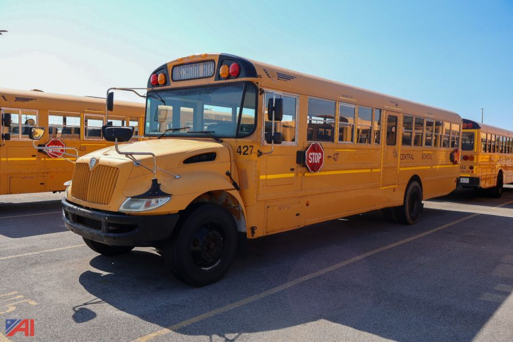 School bus in a parking lot showing front and side view with yellow body and stop sign.