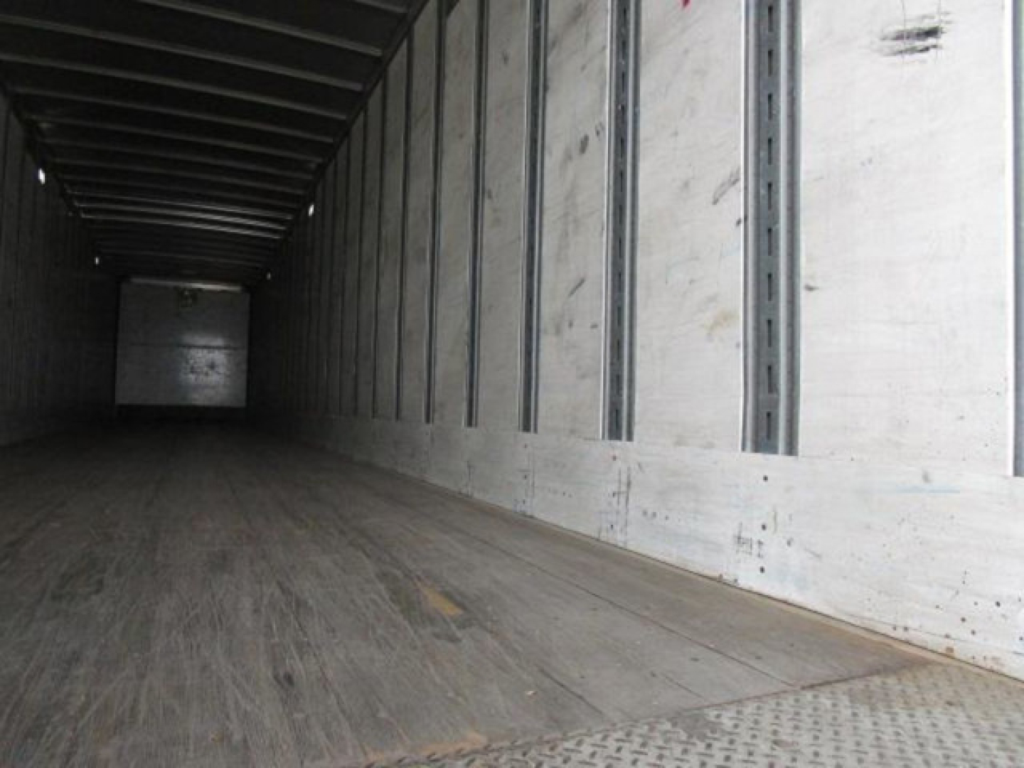 Trailer interior showing long empty cargo bay with wooden floor and metal side walls.