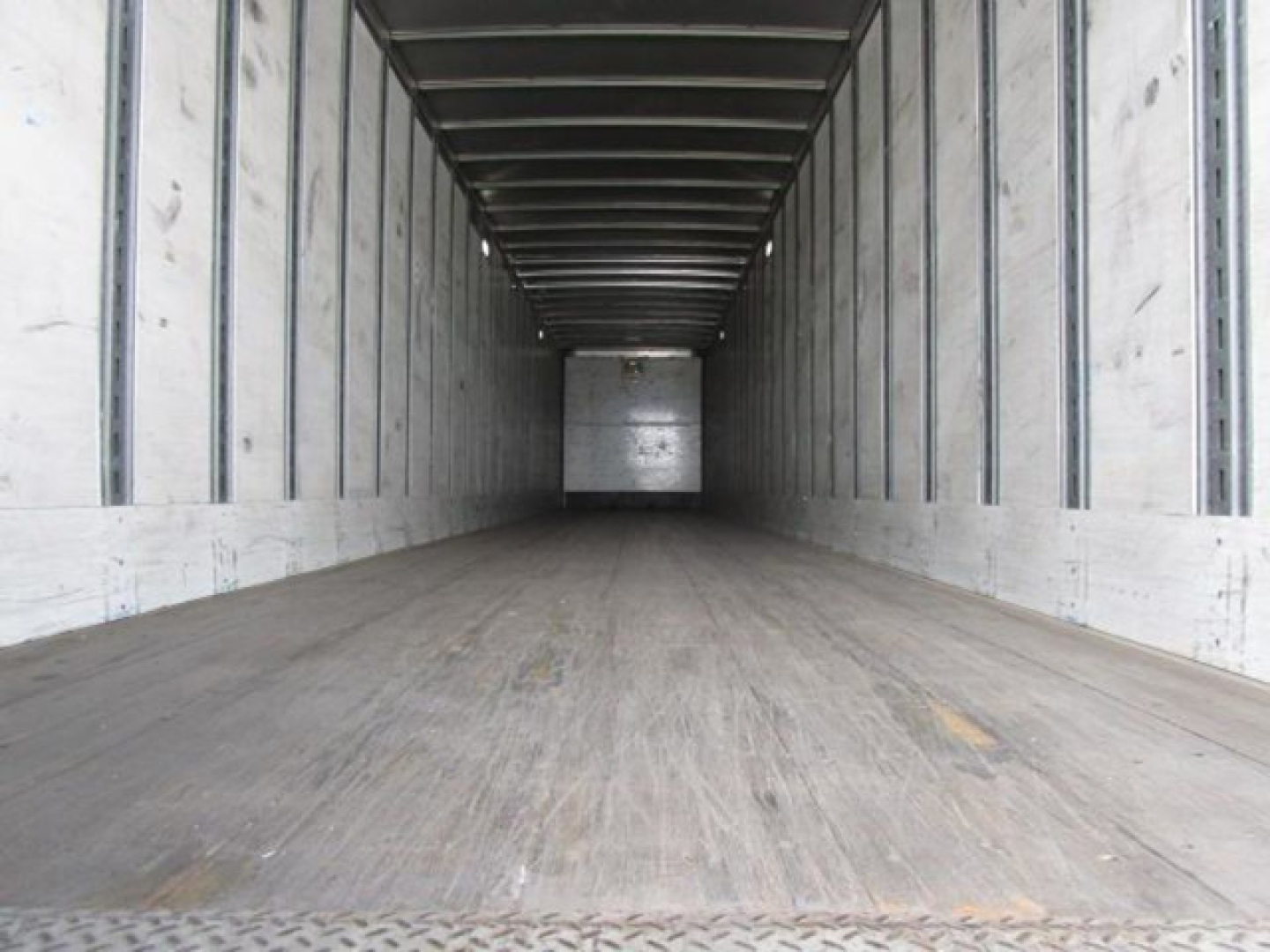 Trailer interior showing empty cargo area with wooden floor and metal side rails in a Stoughton van.