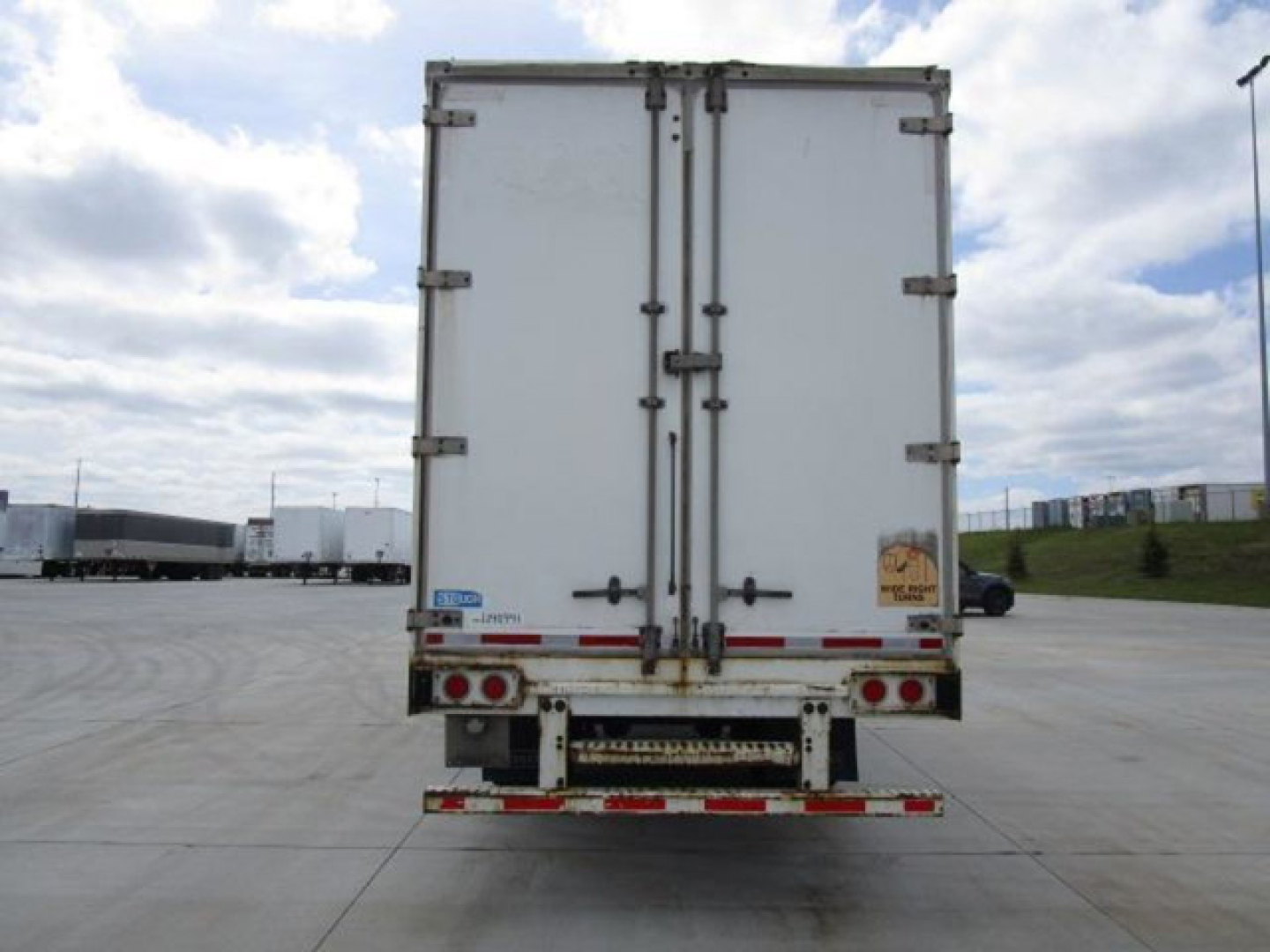 Rear view of a white 2014 Stoughton van trailer with double doors, stock U90991, VIN partially visible, in a truck yard.