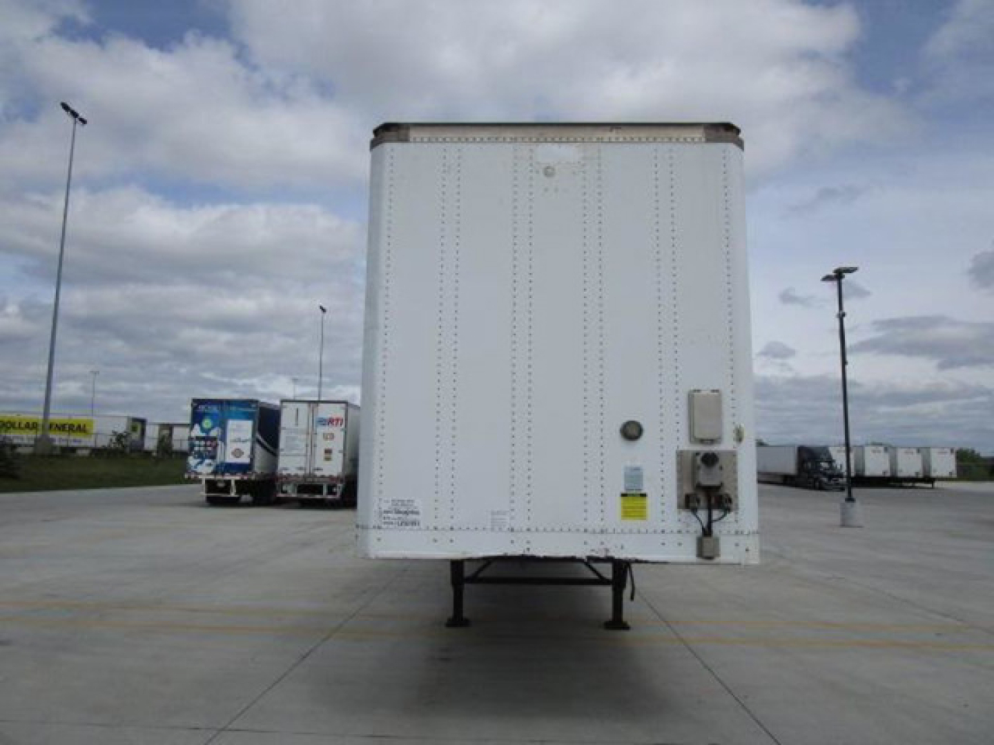 Rear view of a white Stoughton van trailer with reflective panels, taillight area, and electrical connection box on the right side; no legible serial numbers or brand marks readable.