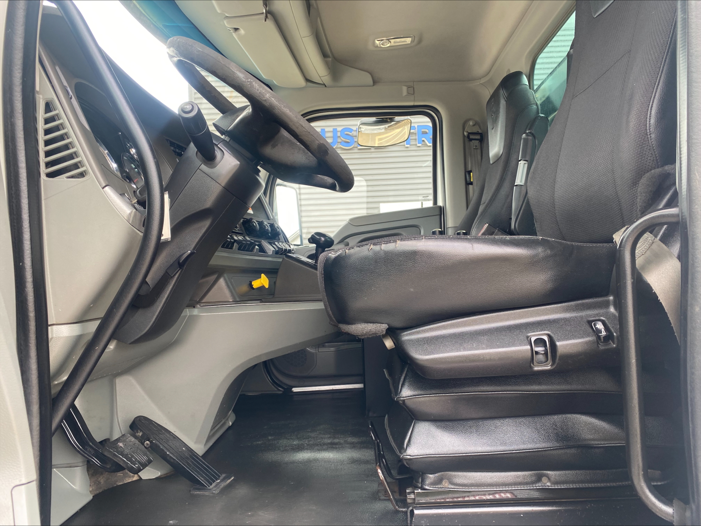 Cab interior of a 2018 Kenworth T880 rolloff truck showing driver's seat, steering wheel, and dashboard with visible controls and pedals.