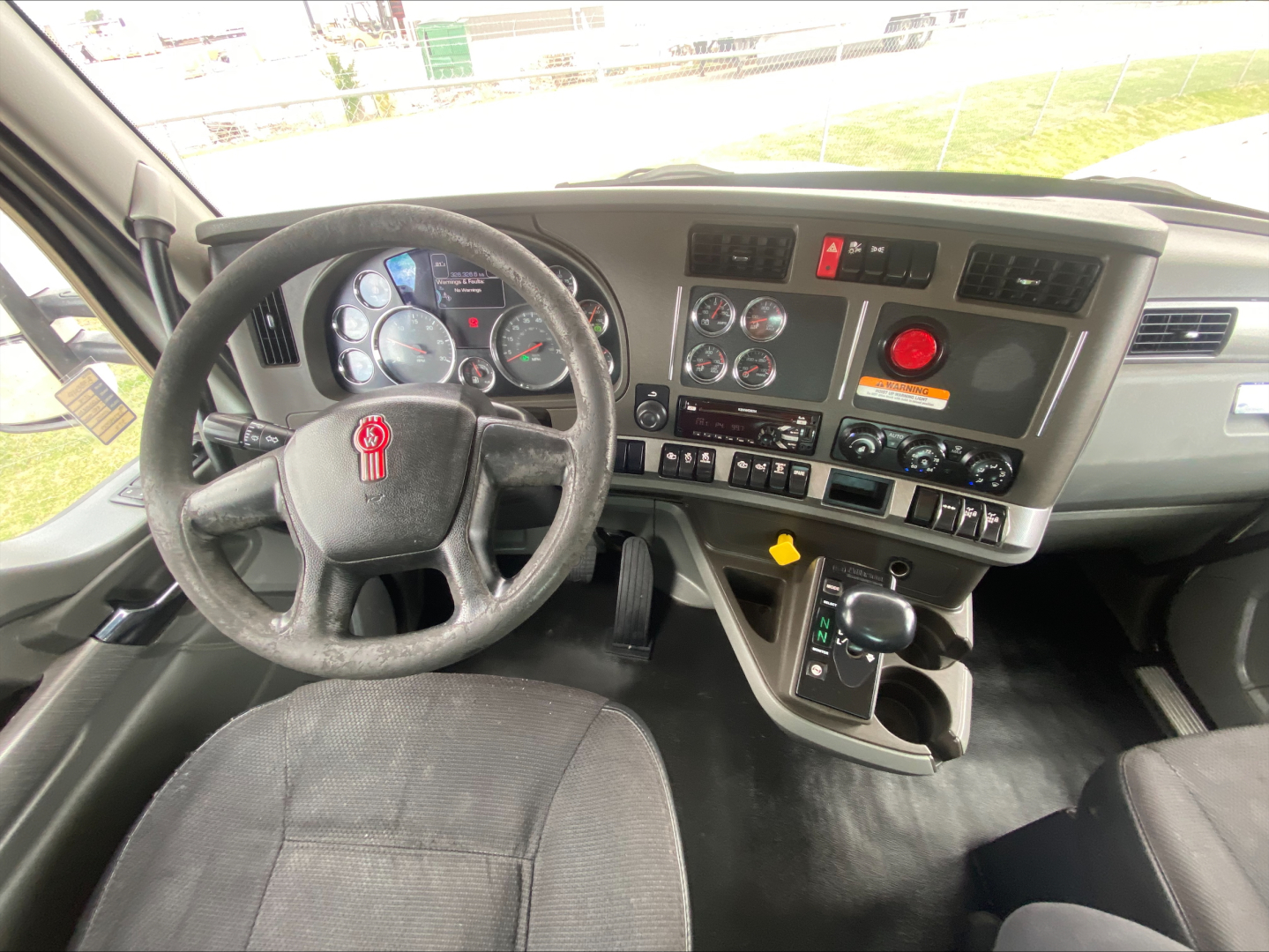 Kenworth T880 cab interior showing steering wheel, dashboard gauges, and center console with controls.