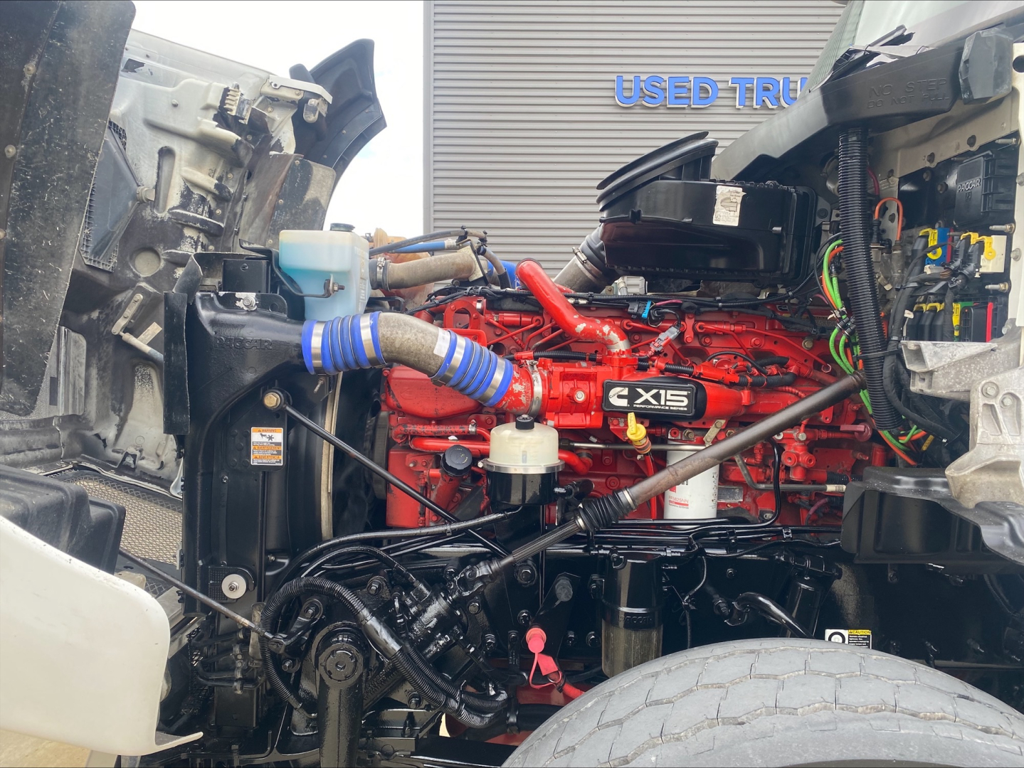 Kenworth T880 engine bay showing red CX15 engine with intercooler piping and surrounding components.