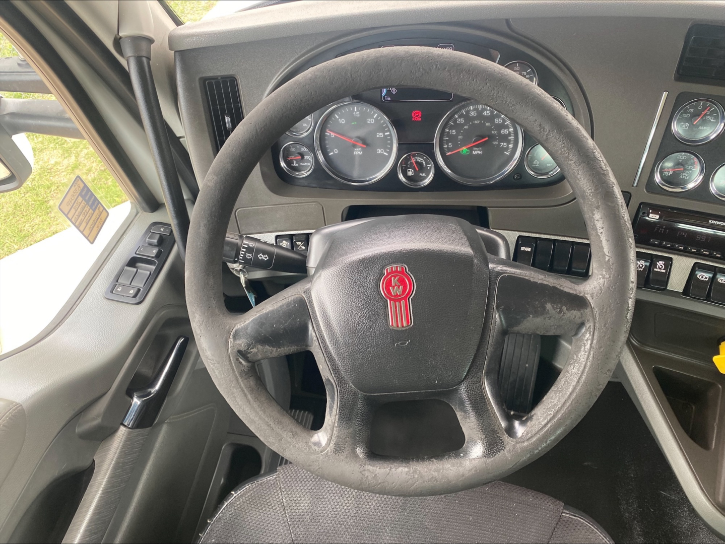 Steering wheel and dashboard of a Kenworth T880 interior with instrument cluster and controls visible.