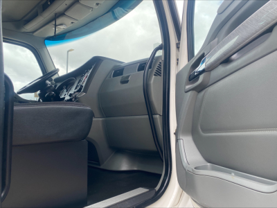 Kenworth T880 cab interior and open driver door showing dashboard and steering wheel.