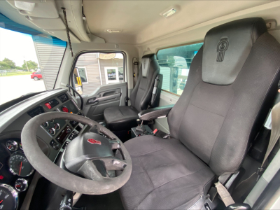 Kenworth T880 truck interior showing steering wheel, driver and passenger seats, dashboard gauges, and center console.