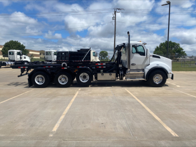 Kenworth T880 roll-off truck side view showing cab and long flatbed with hydraulic system and controls.