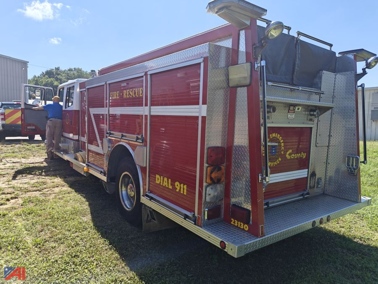 Freightliner FL80 firetruck rear-quarter view showing "Fire-Rescue" livery, dial 911, and metal diamond plate compartments.