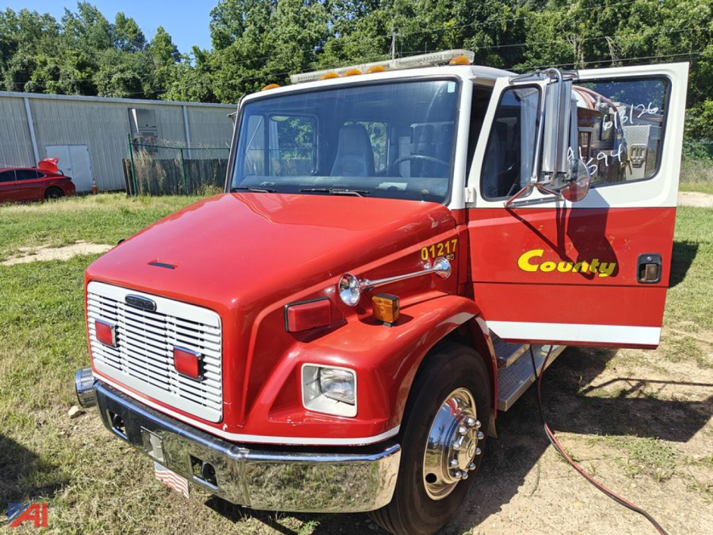 Fire truck cab front and open passenger door showing red body and white grille with amber emergency lights On top.