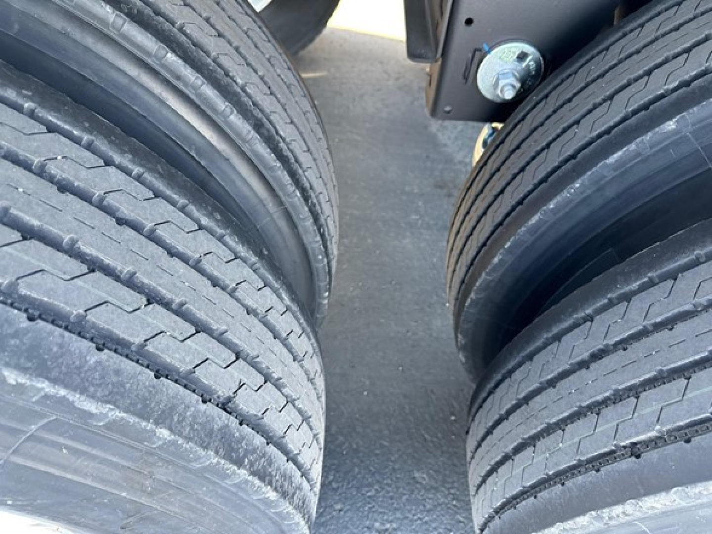Trailer axles with dual wheels showing tread details and suspension components.