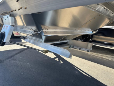 Trailer undercarriage showing aluminum hopper and landing gear with metal support beams and a hinged access step.