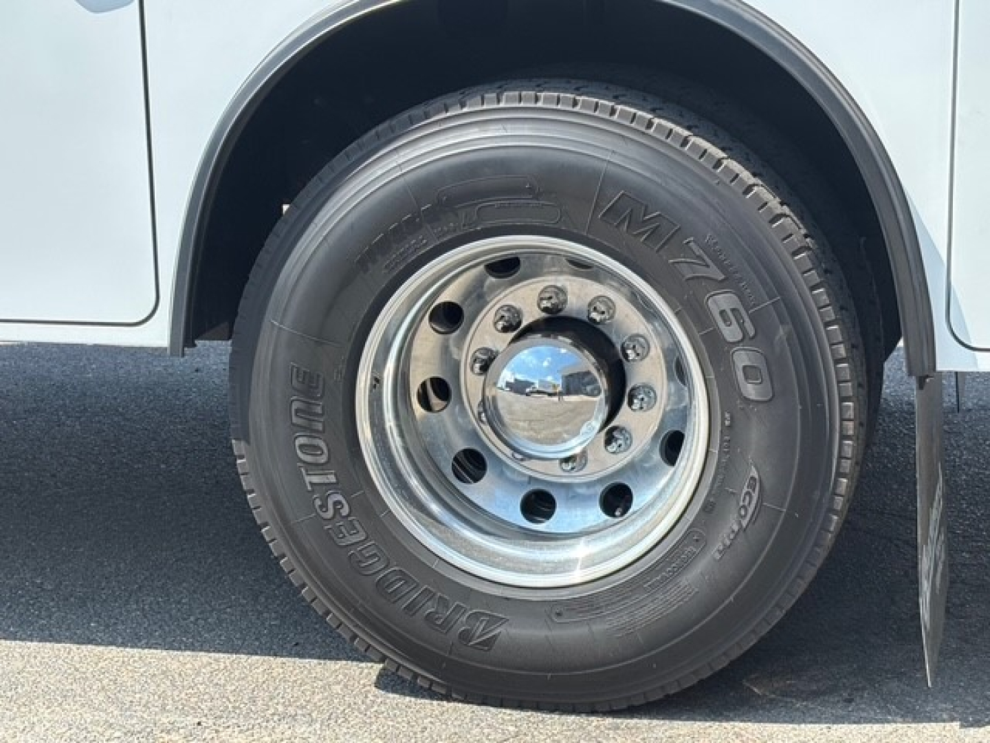 Front wheel of 2026 Mack MD6 service/utility truck showing Bridgestone M77460 tire and polished steel rim.