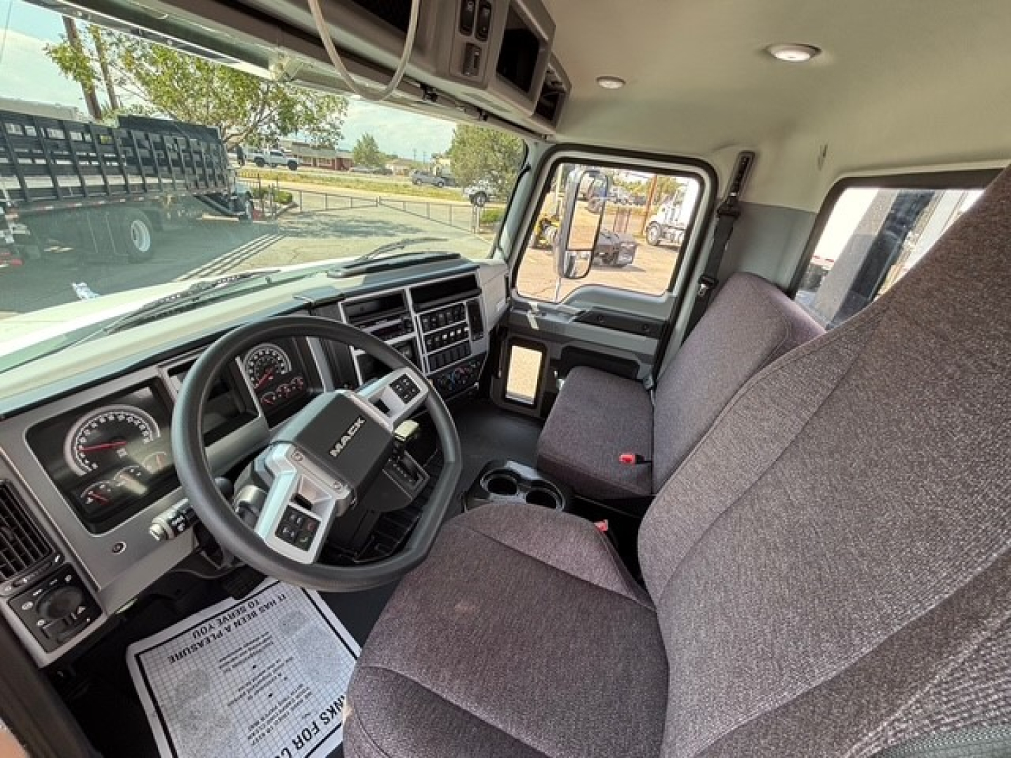 Mack MD6 cab interior showing steering wheel, dash gauges, center console, and front seats.