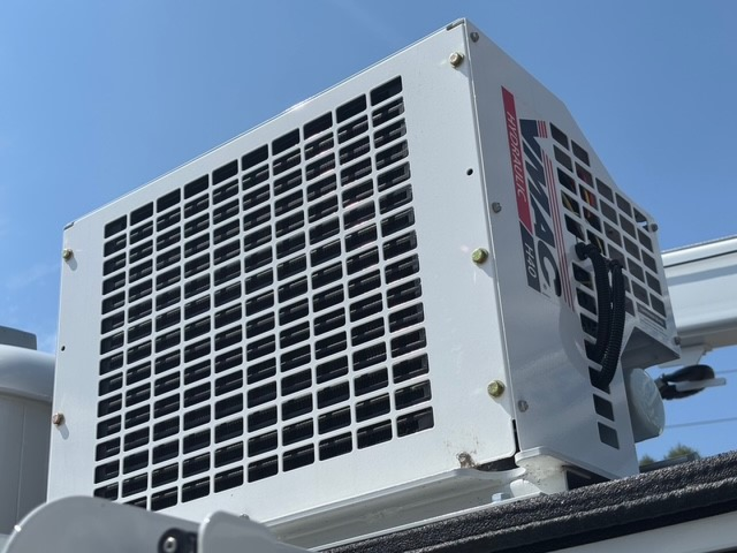 Mack MD6 service truck rooftop A/C condenser unit showing grille and label.