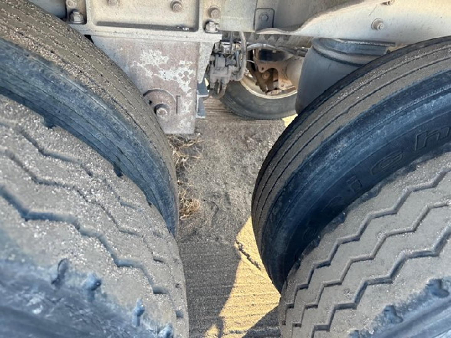 Dual rear tires of a Heil pneumatic trailer showing weathered tread and frame components.
