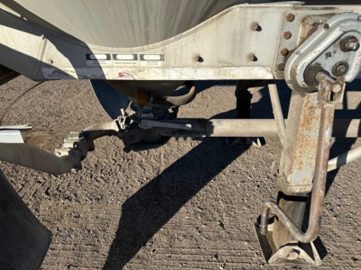 Trailer frame and landing gear of a Heil pneumatic dry bulk trailer showing metal frame, hydraulic/pneumatic components, and a hitch area.