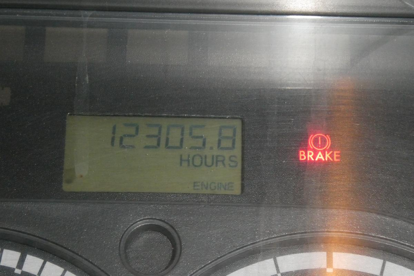 Dashboard gauge displaying 12305.8 hours on the engine hour meter with a brake warning light illuminated.