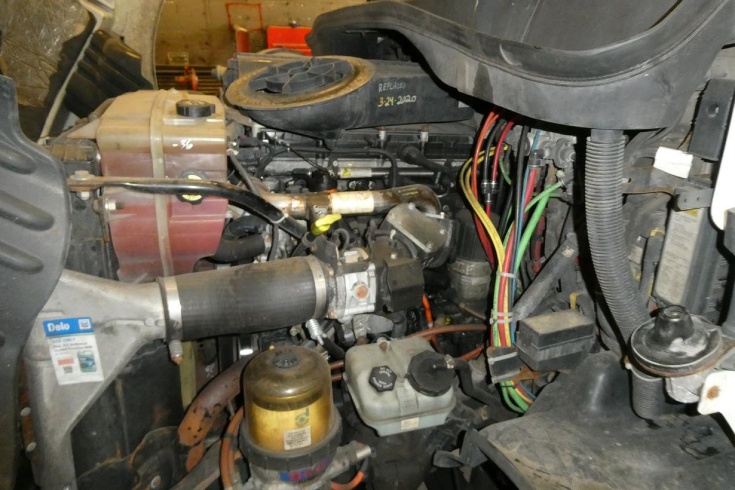 Cab interior view showing diesel engine and hydraulic lines in Freightliner Cascadia 113 engine bay.