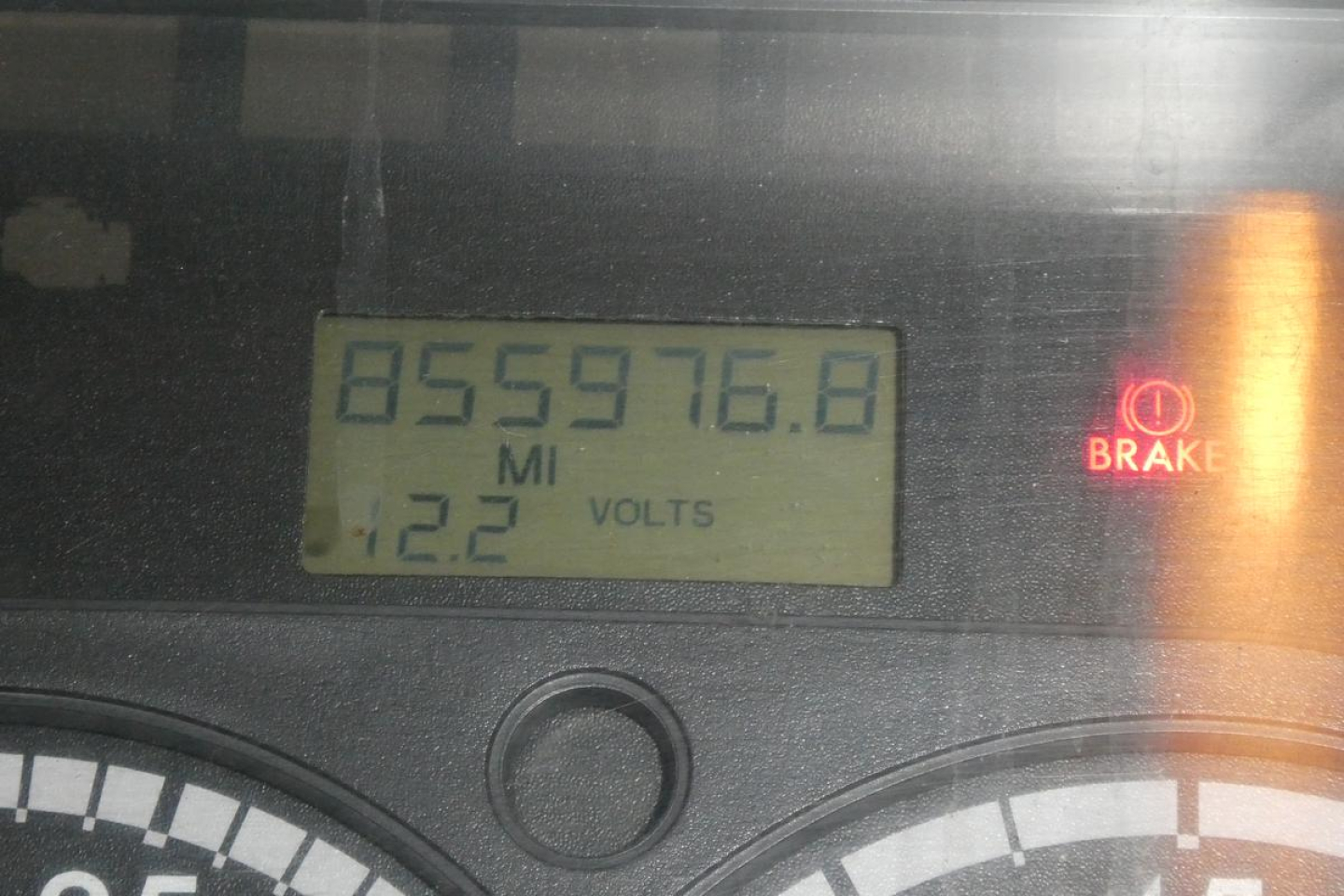 Dashboard odometer reading 855,976.8 miles with 12.2 volts, brake warning light visible on Freightliner Cascadia dash.