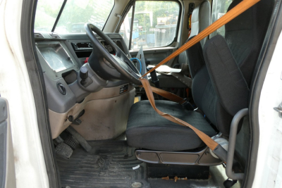 Cab interior of a Freightliner Cascadia 113 daycab showing driver's seat and dashboard with seat belt.