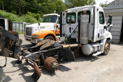 Truck chassis and cab of a Freightliner Cascadia 113 in a yard with another truck in background