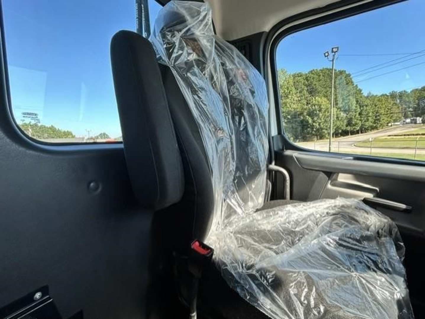 Cab interior of a 2021 Freightliner Cascadia 126 day cab showing plastic-covered seat and window view.