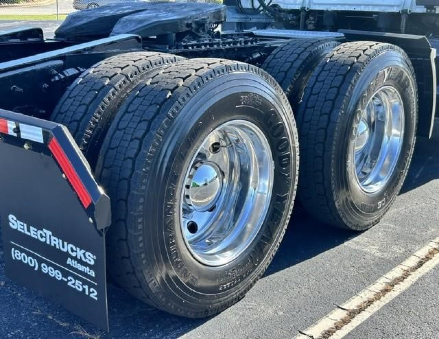 Freightliner Cascadia 126 truck rear wheels and dual tires showing chrome rims and rubber treads, with SelectTrucks sign in foreground.