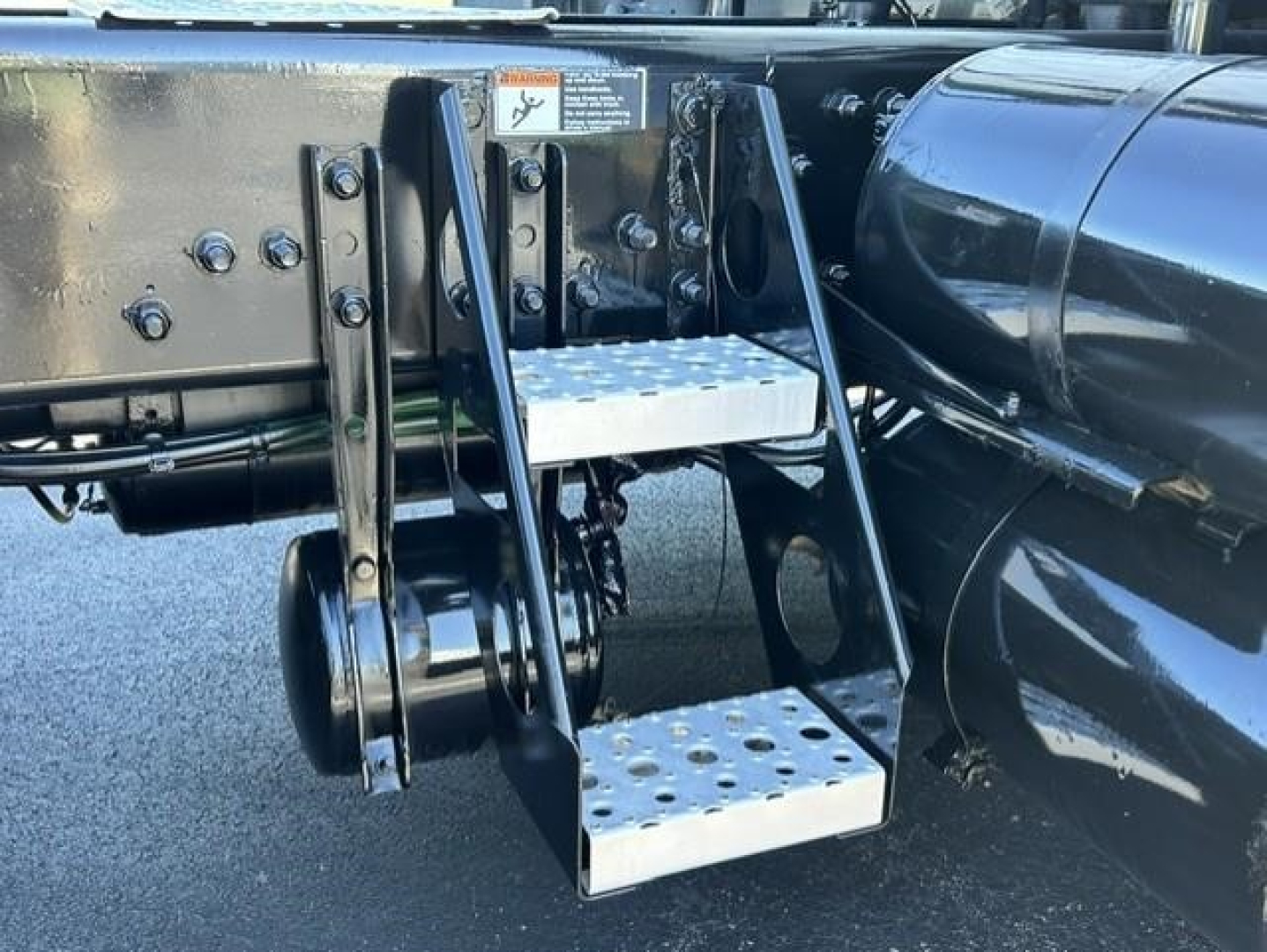 Truck side view showing retractable metal steps attached to a Freightliner Cascadia 126 tractor frame with chrome fuel tank and black chassis.